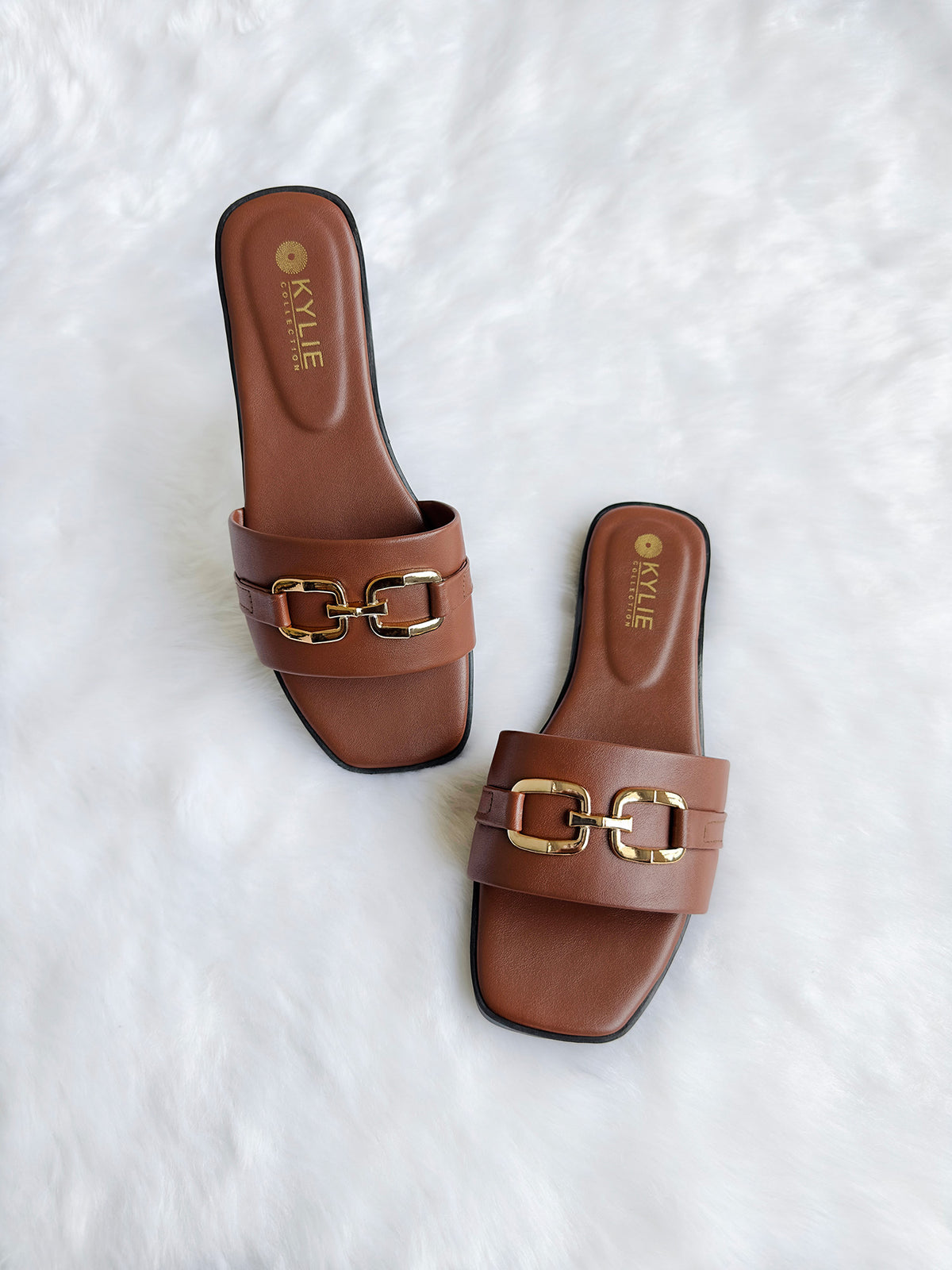Top down view of Kylie Collection ladies brown flat sandals featuring a wide strap with a gold link buckle detail in Sri Lanka