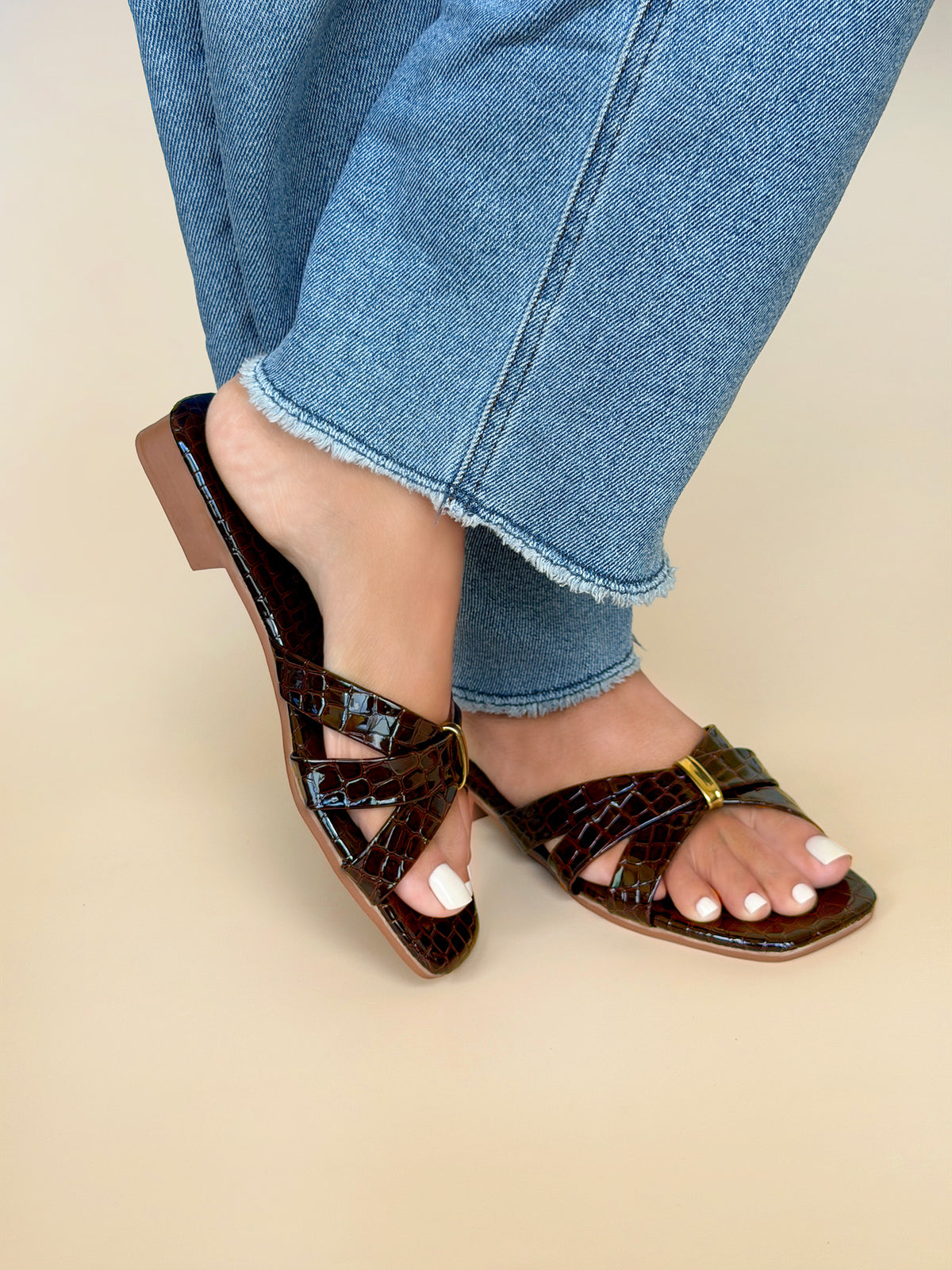 Close up of Kylie Collection ladies coffee brown flat sandals with crocodile texture crisscross straps and a small gold buckle detail in Sri Lanka