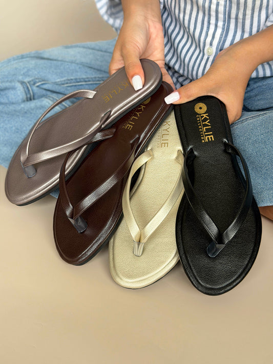 Close up of Kylie Collection ladies silver, brown, gold, and black flat sandals shown on hand with classic thong straps in Sri Lanka