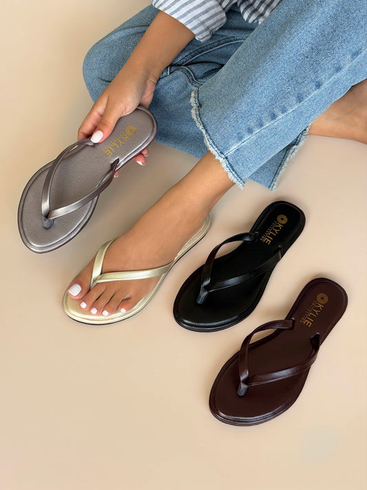 Close up of Kylie Collection ladies silver, gold, black, and brown flat sandals shown on hand and model with classic thong straps in Sri Lanka